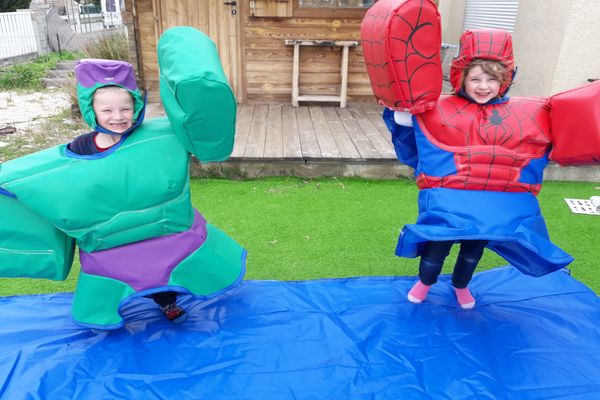 deux enfants qui lèvent les bras. Le garçon habillé en sumo Hulk et la fille habillé en sumos Spider man