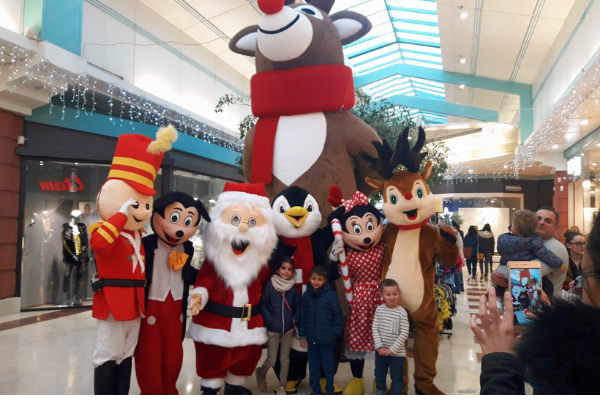 des mascottes en train d'être pris en photos avec des enfants sur une galerie marchande. Mascotte de casse noisette, mickey, pere noel, pingouin, minnie, renne