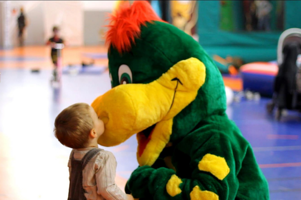 un enfant qui fait un bisou sur le nez d'une mascotte dinosaure