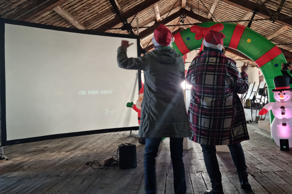 deux personnes chantent devant un écran géant durant la période de noël