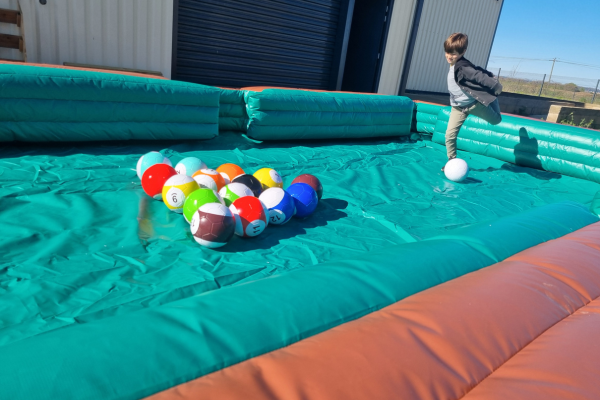 un enfant qui se prépare à tirer sur le ballon blanc dans un billard géant